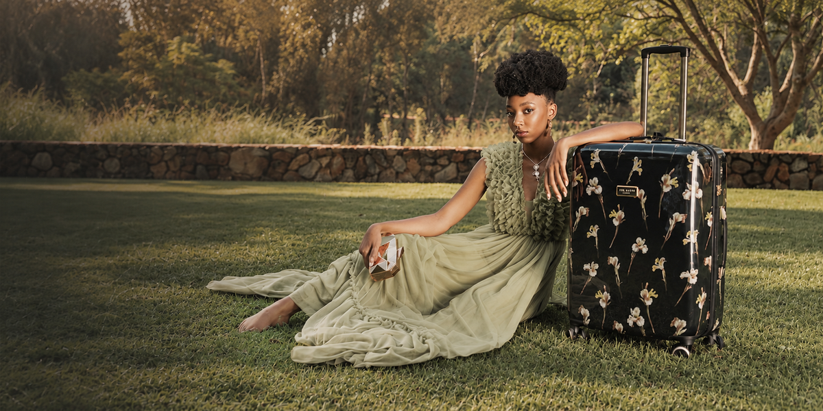 Lady sitting next to a Ted Baker suitcase in a grassy park